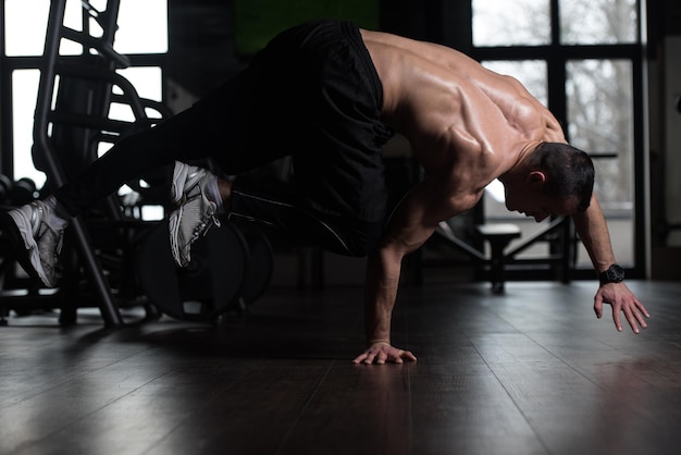 Photo man doing extreme handstand in gym