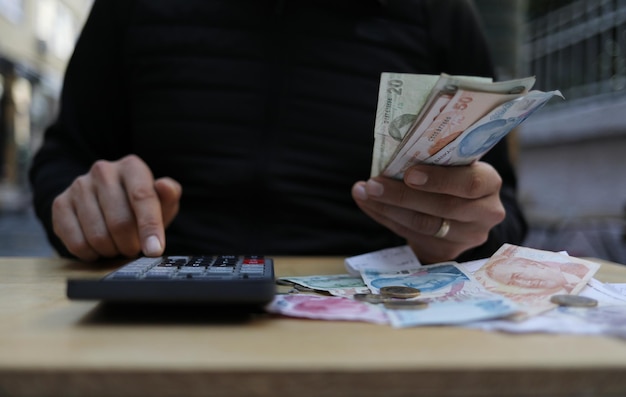 Man doing financial transactions with calculator holding money