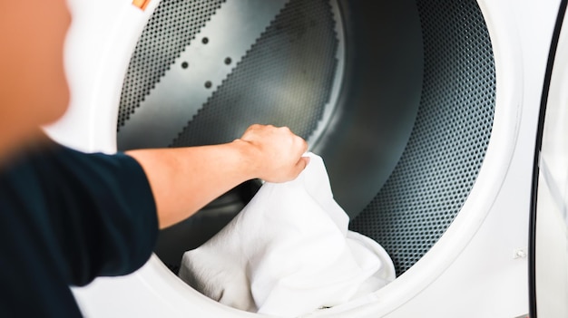 Man doing launder holding basket with dirty laundry of the washing machine in the public store laundry clothes