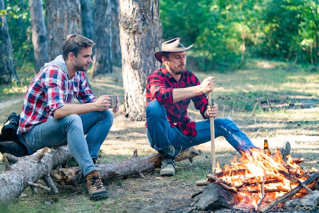 Man doing mans job two friends lumberjack worker sitting in the forest with beer two friends guy cam...