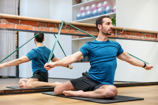 Man doing mermaid Pilates exercise with resistance bands