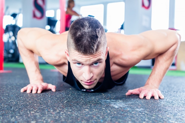 Photo man doing push-up in sport fitness gym