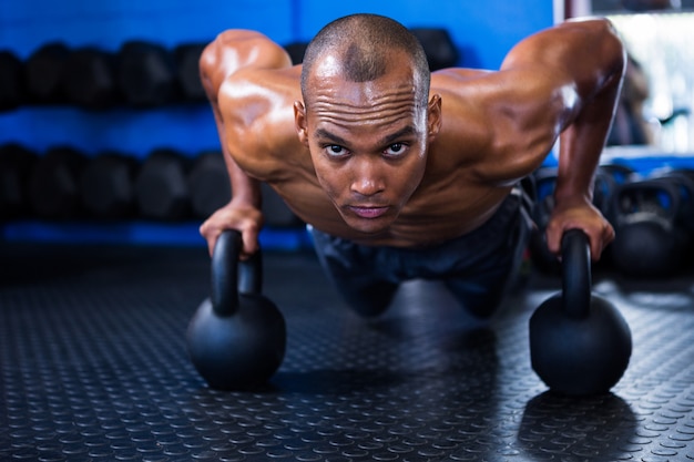 Man doing push-ups with kettlebells