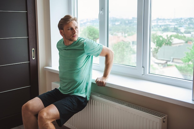 Man doing triceps dip on windowsill at home sporty athletic man fitness instructor exercising workou...