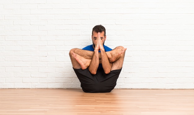 Foto uomo che fa esercizi di yoga al chiuso