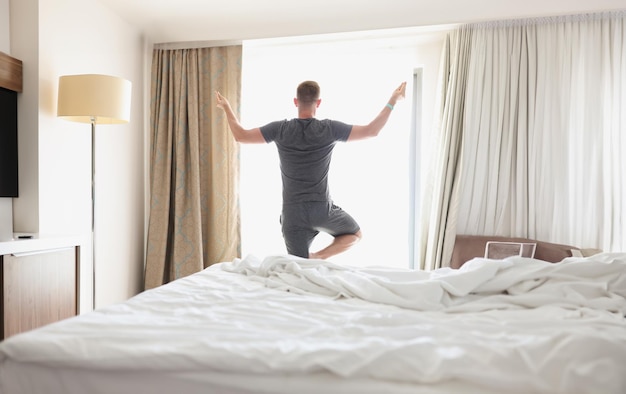 Man doing yoga in front of window in morning