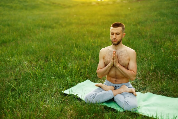 自然の公園でヨガをしている人。瞑想