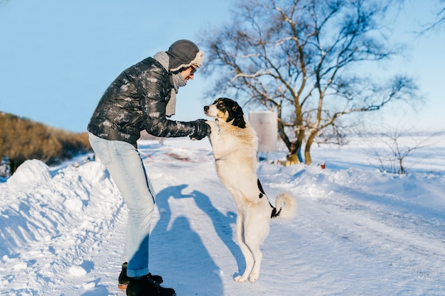 Man in down jacket holding dog paws at winter road