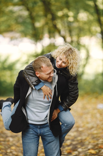 Man draagt zijn vrouw op de rug in het herfstbos