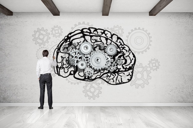 Man drawing brain on concrete wall with cogs