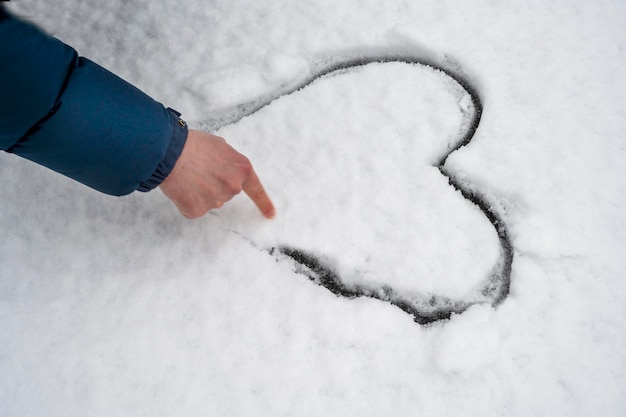 Мужчина рисует форму сердца на снегу зимой Холодное сердце Активный отдых на свежем воздухе