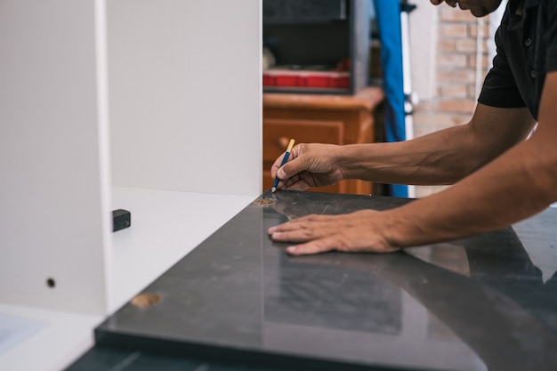 Man drawing a line on a surface in a workshop