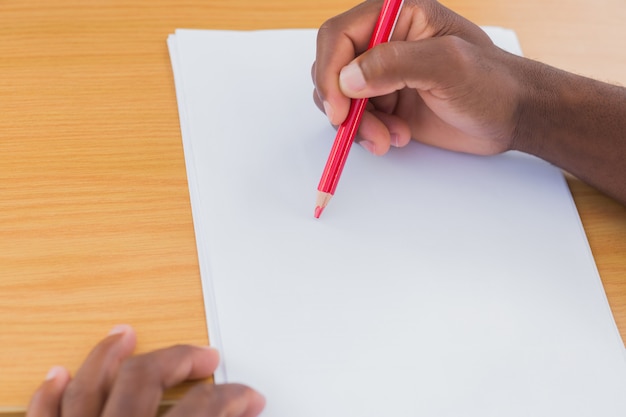 Photo man drawing with a red pencil on a desk