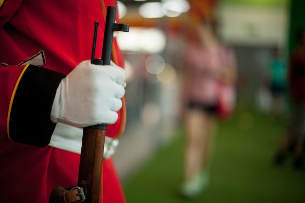 A man dressed as a british guardsman holds a gun in his hand,\
close-up