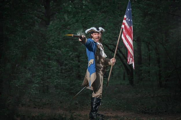 ピストルとフラグを持つアメリカのアメリカ独立戦争の兵士に扮した男