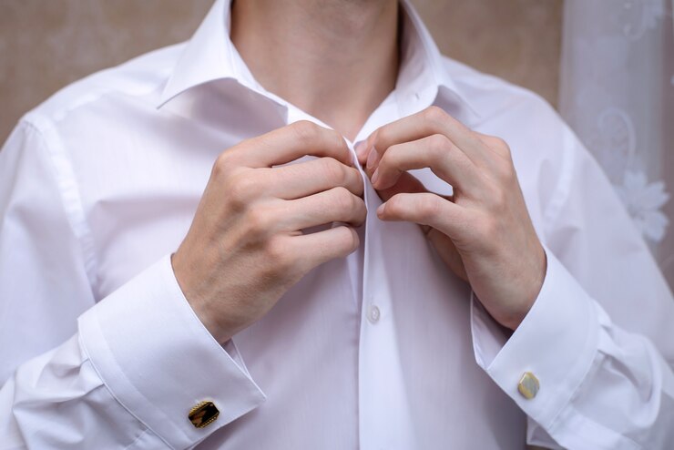 Photo the man dressed and buttoning a white shirt