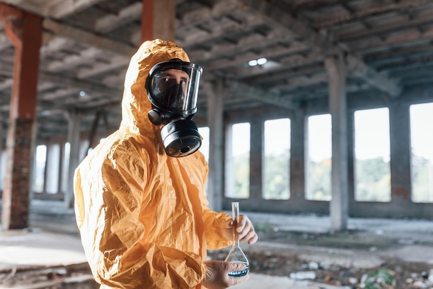 Foto uomo vestito con tuta di protezione chimica che si trova tra le rovine dell'edificio post apocalittico