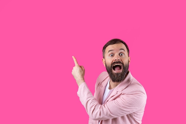 A man dressed in a pink jacket indicates the direction on a pink isolated background