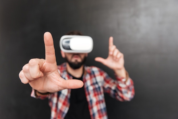 Man dressed in shirt in a cage and wearing virtual reality device standing on chalkboard.