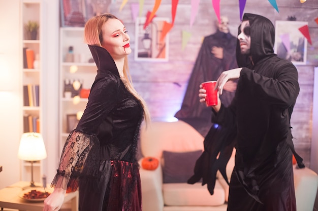 Uomo vestito come un triste mietitore che balla con una bella donna vampiro alla celebrazione di halloween.