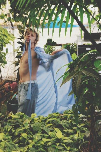 Photo man in dressing gown standing by plants in greenhouse