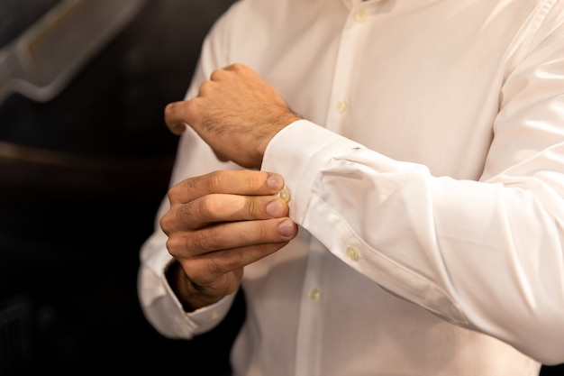 Фото Мужчина наряжается и поправляет белую рубашку с запонками