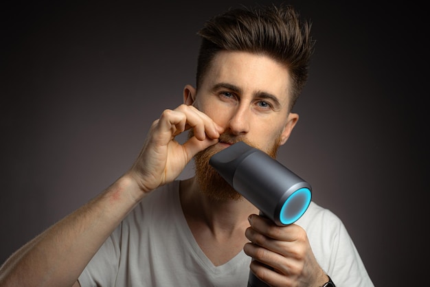 A man dries his beard with a hair dryer