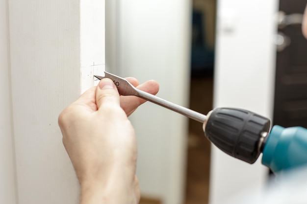 Man drilling a hole in a wooden the door in a room