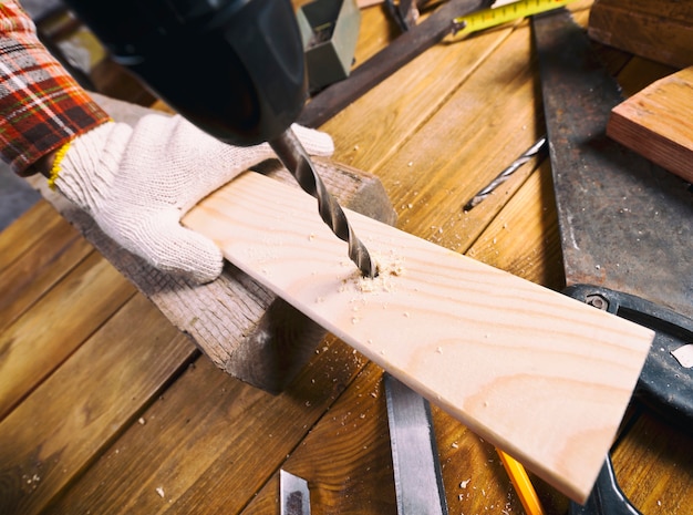 Man drills the wooden plank