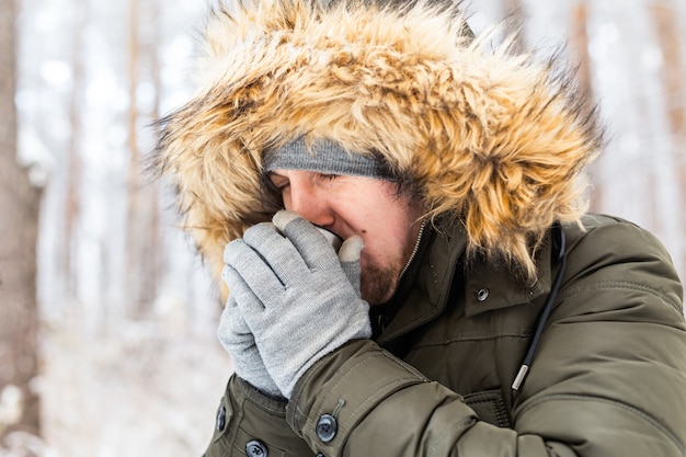 Man drink a hot drink from a thermos and enjoy winter nature.