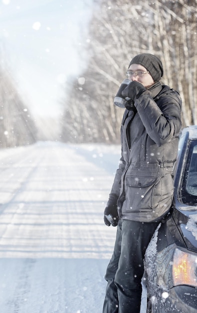 Man drink hot tea from mug outdoor on winter road