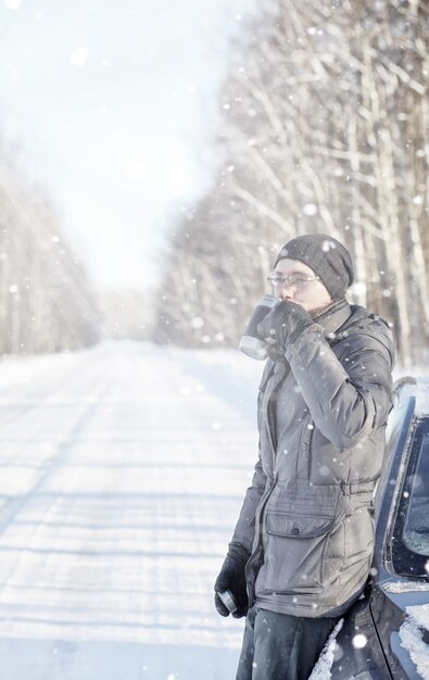 Foto l'uomo beve tè caldo dalla tazza all'aperto sulla strada invernale