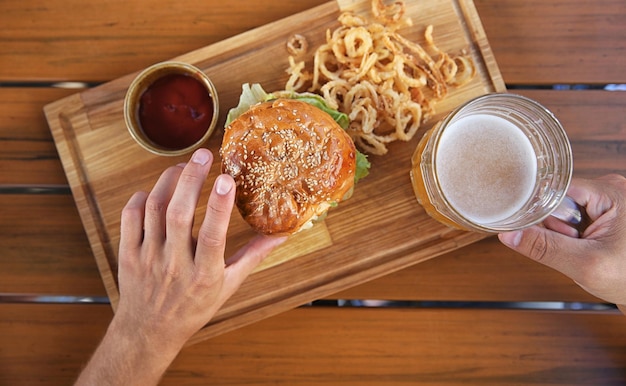 Man drinking beer and eating snacks on wooden background