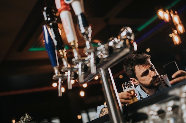 Foto uomo che beve birra e fumo di sigaretta al pub nel night club