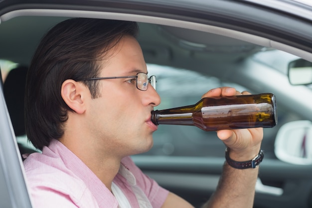 写真 運転中にビールを飲む男