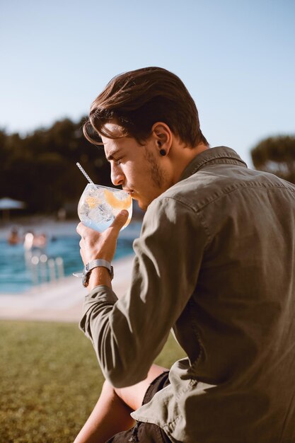 Uomo che beve un cocktail vicino alla piscina - primavera ed estate