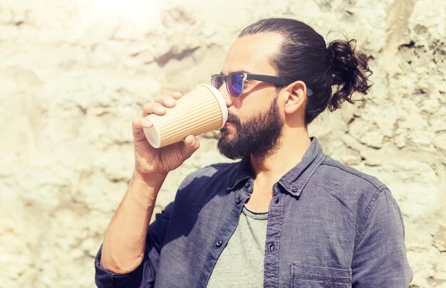 写真 路上で紙コップからコーヒーを飲む男性