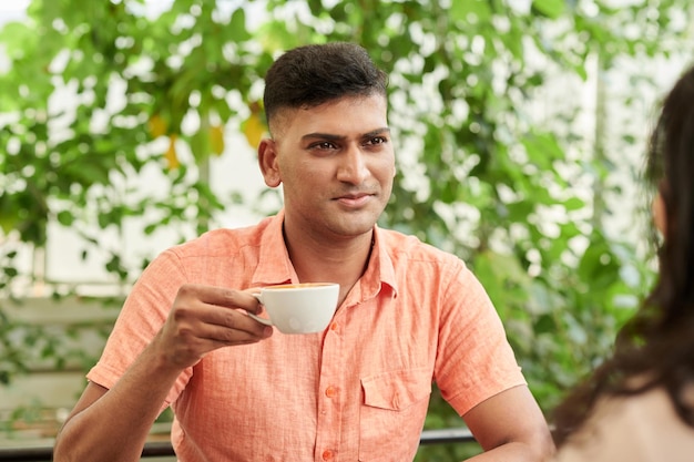 カプチーノのカップを飲む男