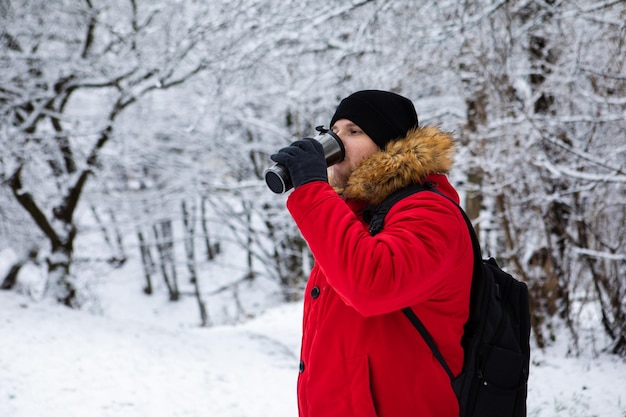 man drinking warm up drink outside at cold snowed winter day
