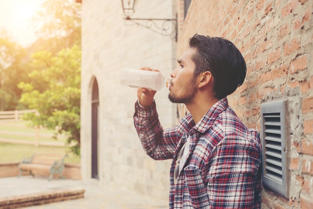 Man drinking water from bottle against brick wall