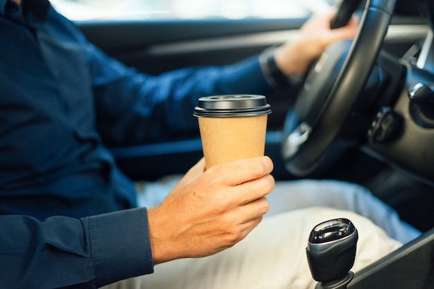 男は車の中でコーヒーを飲む