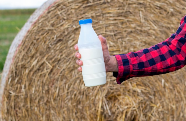 Photo man drinks fresh bio milk on the field, hay, grass, farm