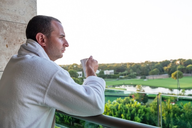 A man drinks tea on a hotel balcony on vacation. Summer concept