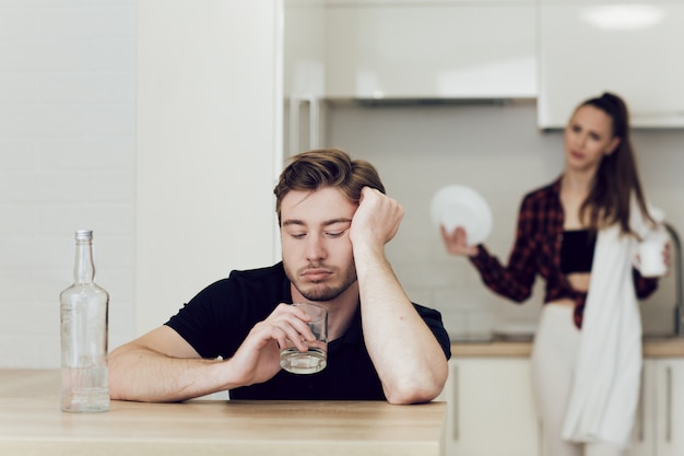 L'uomo beve mentre è seduto a un tavolo in cucina