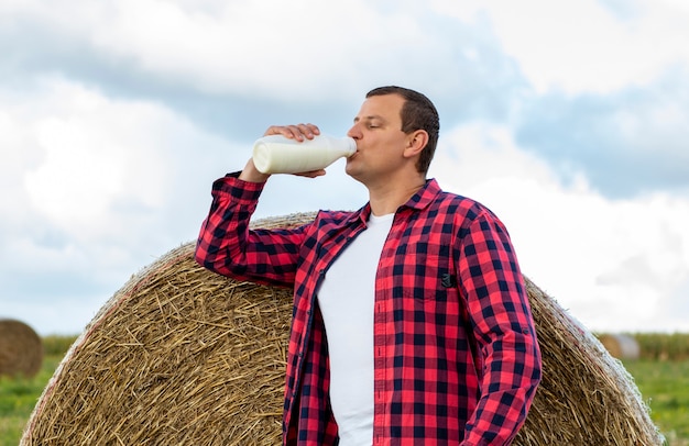 Man drinkt verse biologische melk op het veld, hooi, gras, boerderij