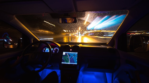 The man drive with a gps on the night road. Inside view. Wide angle