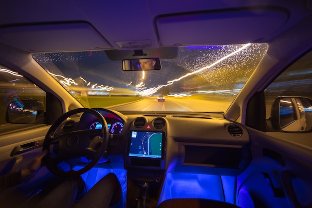 The man drive with a navigation on the night highway. Inside view