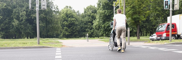 Man drive woman on wheelchair across street at pedestrian crossing