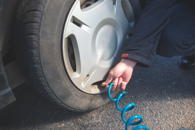 Man driver checking air pressure and filling air in the tires of his modern car, transportation concept