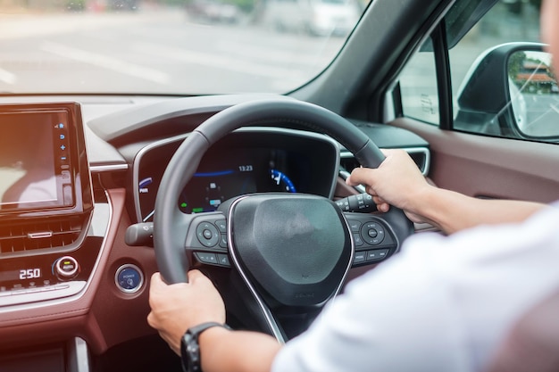 Autista uomo che guida un'auto sulla strada che controlla a mano il volante in un'automobile elettrica moderna viaggio di viaggio e sicurezza concetti di trasporto